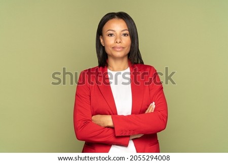 Confident african american businesswoman studio portrait with folded hands. Successful young girl entrepreneur wearing elegant red jacket isolated over empty wall. Female leader and leadership concept Royalty-Free Stock Photo #2055294008