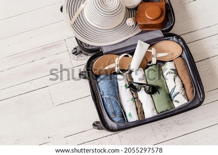 Luggage and suitcase packing for vacation on white wooden background in studio  Royalty-Free Stock Photo #2055297578
