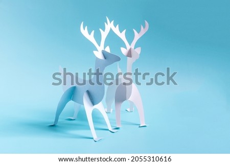 Origami paper deer in blue and white on a bright blue background.