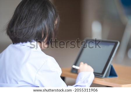 Asian child student studying and writing on a digital tablet outdoor education school. Back to School Concept Stock Photo