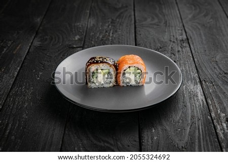 Japanese cuisine. Rolls on a round plate on a black table.
