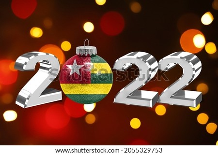 Colorful blurred background and applied the flag of Togo on the New Year's toy. New Year 2022 Celebration