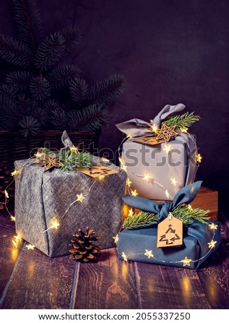 Three Eco-friendly furoshiki style gift wrapped boxes on dark background with lights. Zero waste Christmas Recycle, Reuse, Sustainable lifestyle concept.