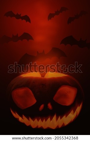 Scary halloween background - glowing pumpkin with face and silhouettes of bats