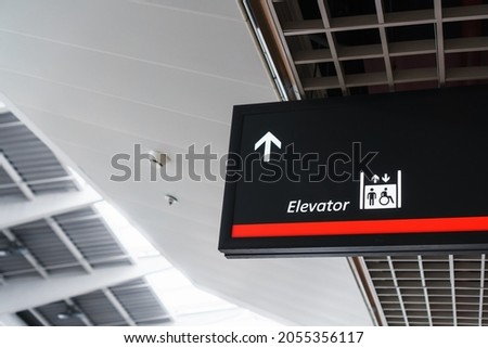 A sign with an arrow pointing to the elevator in the airport waiting terminal. Copy space