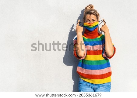 Young woman put off gay pride face mask during Coronavirus pandemic in rainbow colors symbol of Lgbtq social movement concept image, with copyspace for your individual text.