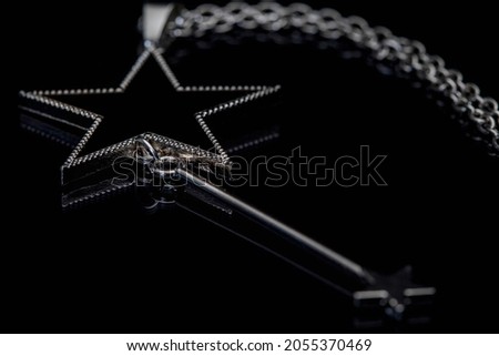 A closeup shot star design necklace,  with a smaller star which hangs below.