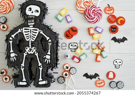Halloween skeleton piñata with treats and candies around