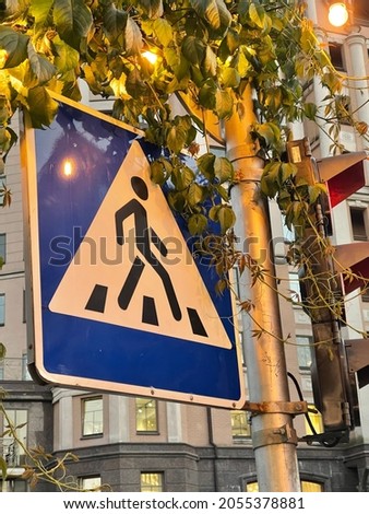 Vertical shot of pedestrian  crosswalk sign in the leaves