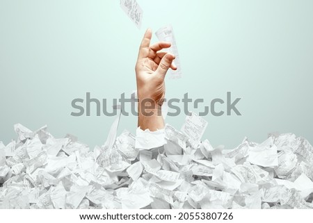A man's hand sticks out of a mountain of checks and bills. A man is drowning in debt, credit, mortgage, loan, mortgage Royalty-Free Stock Photo #2055380726