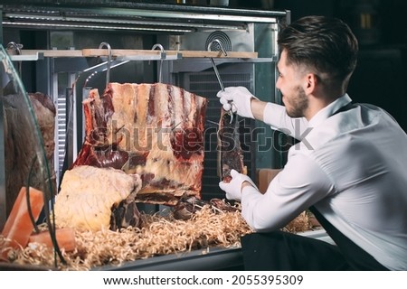 The waiter or cook gets dry meat in the refrigerator Royalty-Free Stock Photo #2055395309