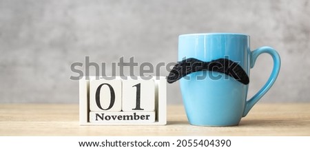 November 1 calendar, Blue coffee cup or tea mug and Black mustache decor on table. Men day, Happy father day and Hello November concept Royalty-Free Stock Photo #2055404390