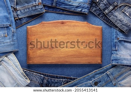 Blue jeans denim and sign wood name plate. Jeans heap with wooden nameplate background texture Royalty-Free Stock Photo #2055413141