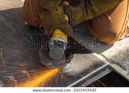 cleaning of metal from welds. advertising picture. the usual job. a man works with a grinding machine. lots of sparks.