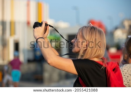 A woman takes pictures on the street in the city