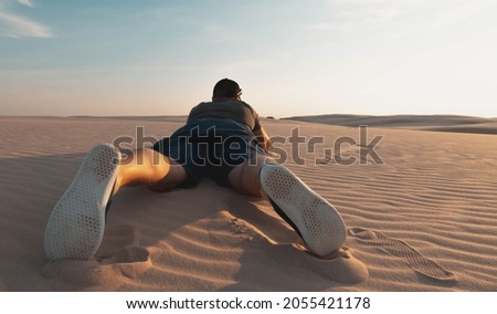 Traveler hiker lies on the sand and takes a picture at sunset. Wide angle shot.
