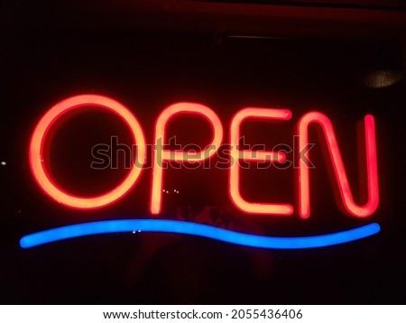 Neon red and blue open sign with a black background.