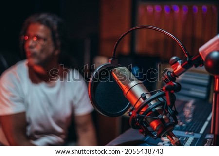 Microphone in music studio with the music producer sitting in the background