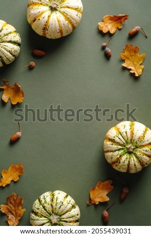 Autumn composition. Flat lay pumpkins, dry oak leaves, acorns on vintage green background. Thanksgiving day vertical banner design.