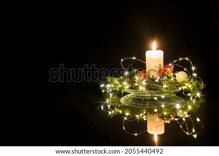 Christmas floral decoration with candle and dark background.
