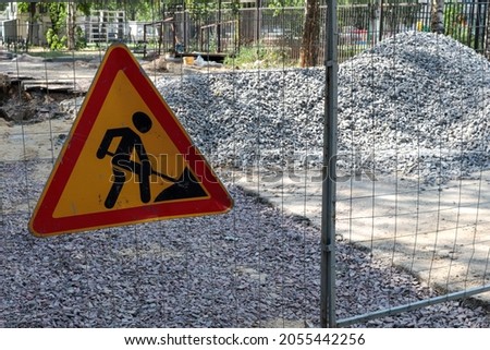 Road works. Road sign on the fence against the background of heaps of rubble