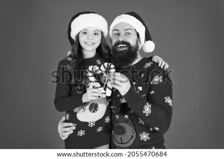 Playing together. Santa claus family look. Bearded dad and little girl. Christmas games. Joy and happiness. Christmas Carol. Father and daughter with candy canes christmas decorations. Family holiday