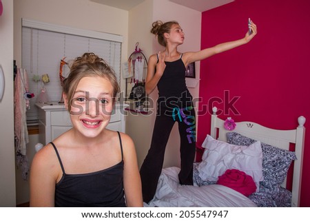 Two young girls playing in a room and taking a selfie