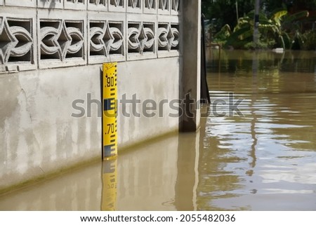 Selective focus water level indicator installed at wall for measuring water level while flooding along local road in countryside of Thailand. It's nature disaster.                              