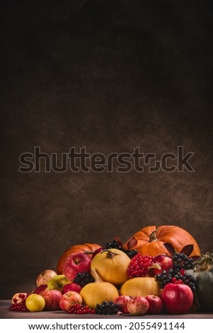 Thanksgiving background. Festive still life with pumpkins, berries, autumn leaves and apples on dark brown background with copy space. Happy Thanksgiving day, autumn harvest, Halloween. Vertical