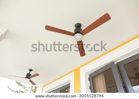 ceiling fan with wooden blades hangs from white ceiling.