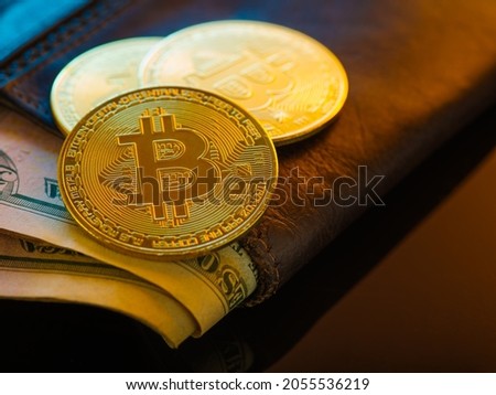 Brown wallet with American dollars and gold bitcoins. Brown background. Close-up. Minimalism. Cryptocurrency, internet trading, financial flows, e-commerce, new financial technologies.