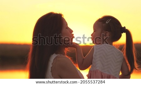 little girl kisses her mother at sunset, happy family, childhood dream, mom hugs her beloved daughter in the rays of sunshine, kid's trip on a weekend with a parent, kissing baby on the lips