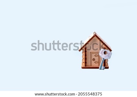 Wooden house model and key on blue background. Concept of buying and selling homes and real estate. Home Insurance, property and mortgage. Copy space for text
