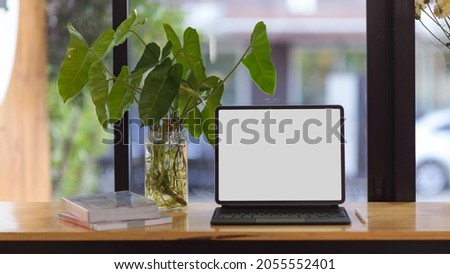 Portable tablet in blank screen mockup for montage your picture on screen stand on wooden table over blurred background
