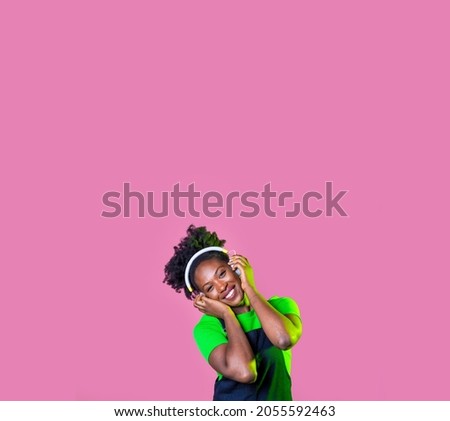 Young curly hair black woman isolated dancing listening music with wireless headphones - advertising copyspace