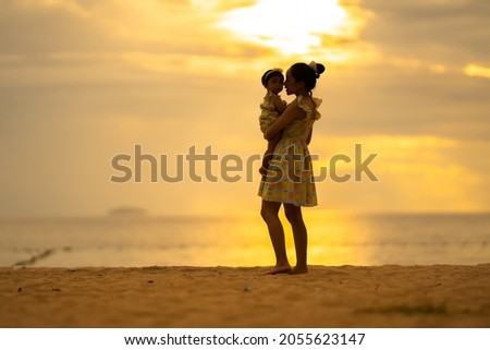 Silhouetted Mother holding baby with happy moments at sea in the evening