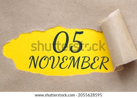 november 05. 05th day of the month, calendar date.Hole in paper with edges torn off. Yellow background is visible through ragged hole. Autumn month, day of the year concept.