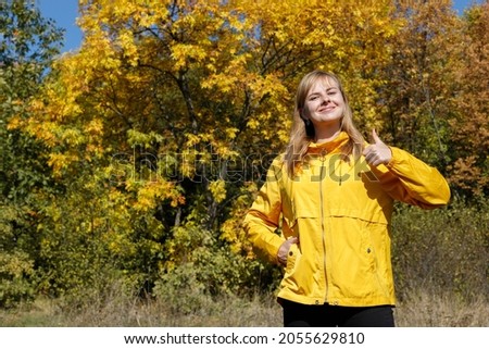 a young woman shows class an autumn yellow tree. free space for text