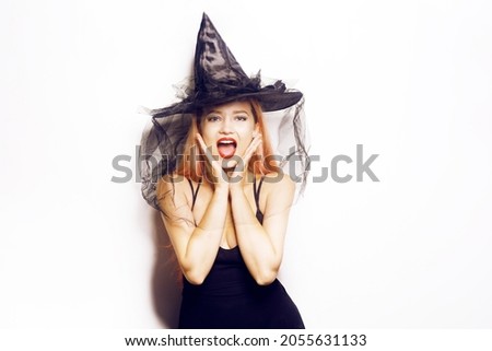 A beautiful girl witch in shock celebrates Halloween, joy and delight on her face. The model looks at the camera in shock.