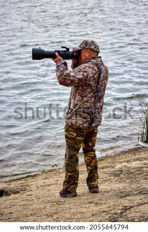 professional photographer in camouflage clothes working in nature. autumn day.