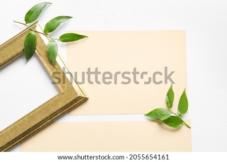 Composition with blank cards, empty picture frame and leaves on white background, closeup
