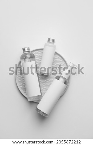 Different bottles of cosmetic products on light background