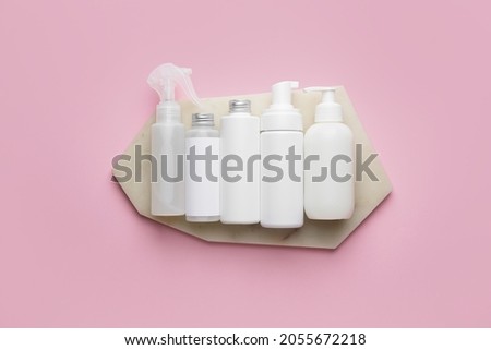 Different bottles of cosmetic products on color background