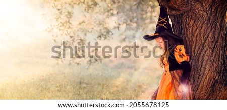 Magic picture from copy space on Halloween, girl witch conjures magic, leaning on a tree