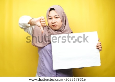 Pretty young muslim woman dislike, hand holding blank empty banner, placard, white board, blank sign board, white advertisement board, presenting something in copy space, promotion
