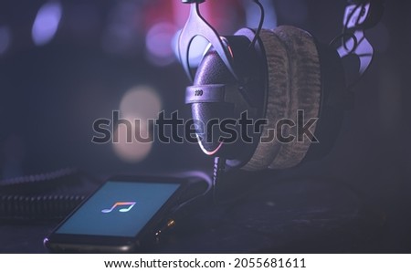 Phone with music icon and headphones on blurred background, music listening concept, copy space.