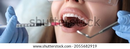 Doctor dentist making injection with anesthetic into gum of woman patient closeup Royalty-Free Stock Photo #2055682919