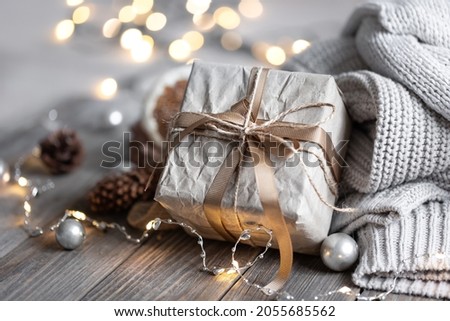 Close-up of a gift box, details of a festive Christmas decor and knitted elements on a blurred background with bokeh.