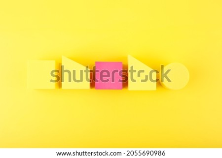 Yellow minimal abstract composition with yellow and pink geometric shapes in a row against yellow background. Individuality and being different concept. 