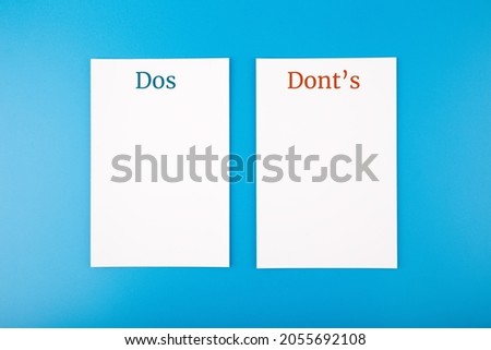 Dos and dont's business or personal concept on blue background. Two white sheets of paper with written words dos and dont's on bright blue background with copy space